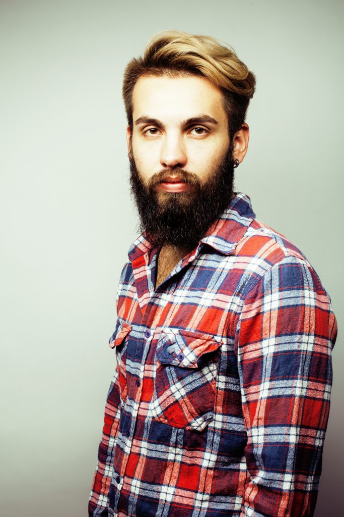 portrait of young bearded hipster guy smiling on white background close ...